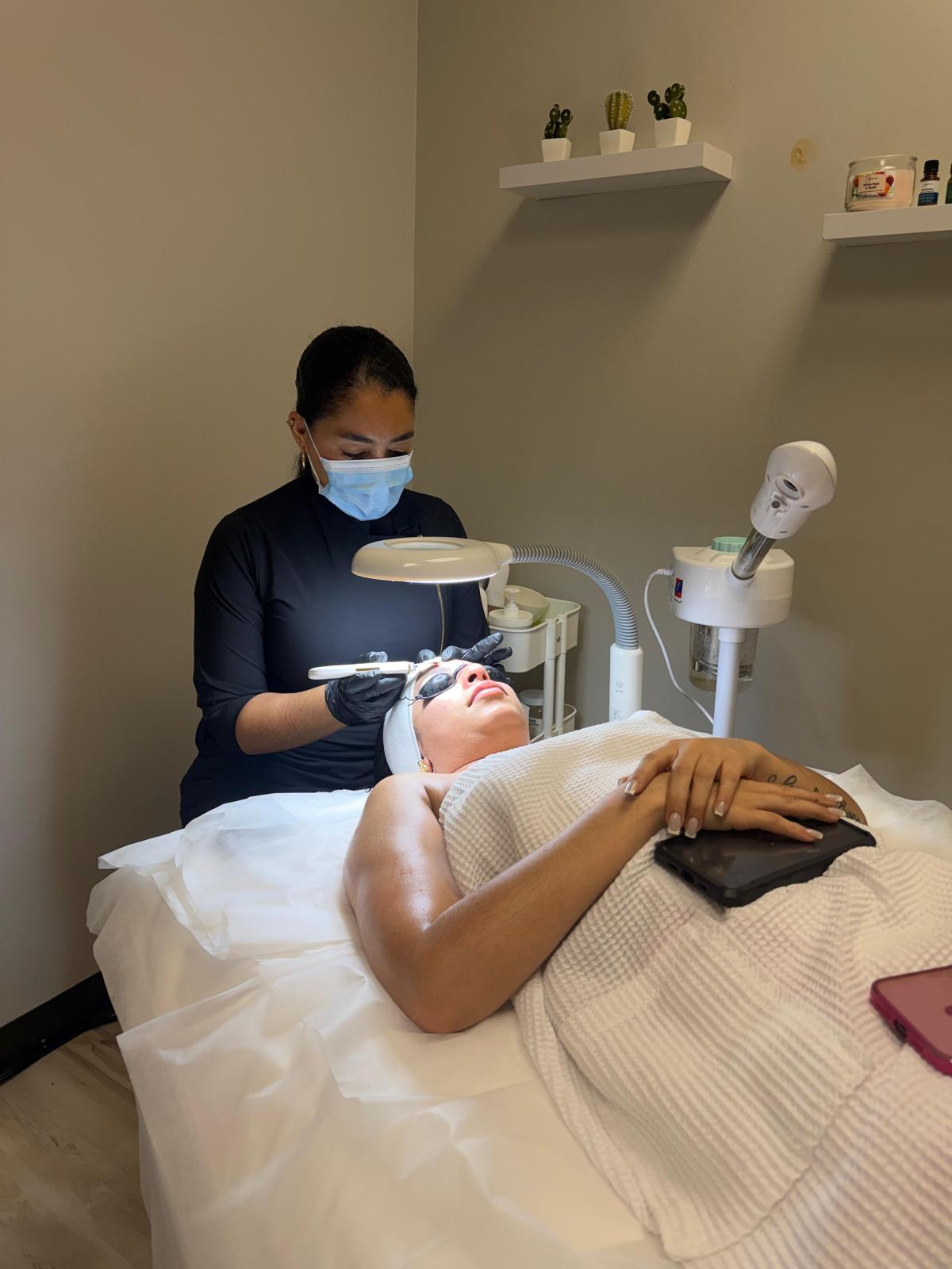 Especialista de Body Wellness TX aplicando un facial a una clienta en cabina / Body Wellness TX specialist giving a client a facial in the treatment room